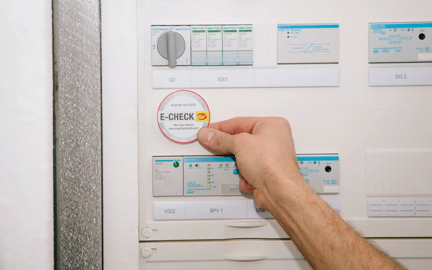 E-CHECK - Mitarbeiter klebt in der Verteilung die E-CHECK Plakette an &middot; Elektro-Diehm